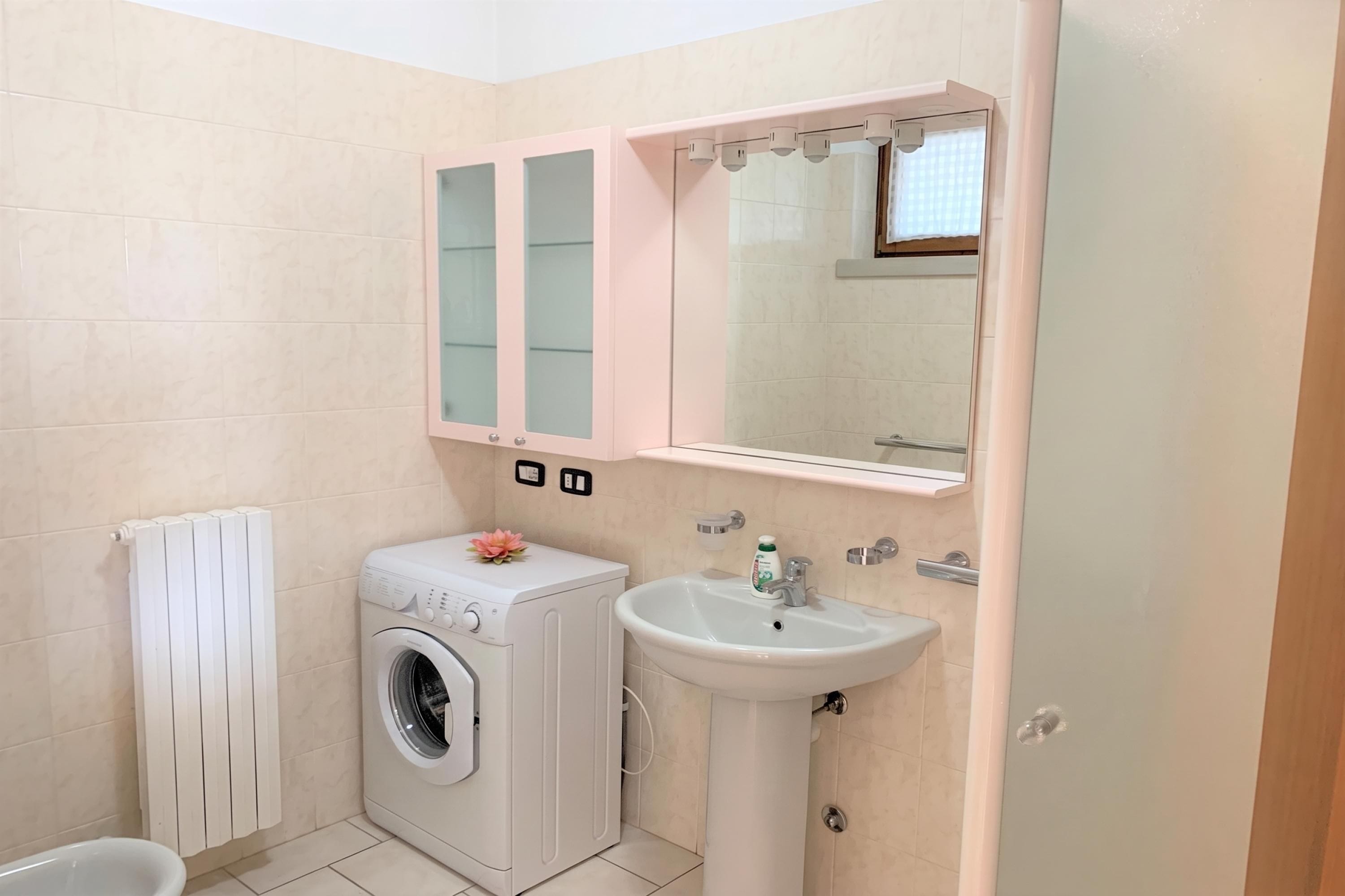 Un baño pequeño con lavadora, lavamanos e inodoro.