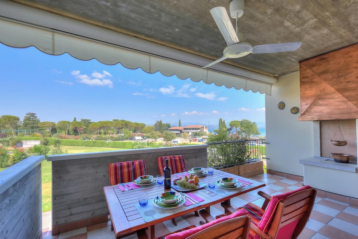 A balcony with a table set for dining, a ceiling fan, and a view of the landscape.