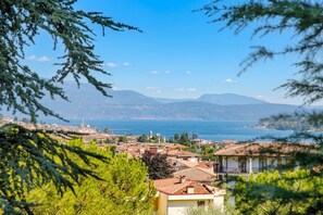 A coastal town with buildings, a clear sky, and mountains in the background. - Villa Alberti Appartamento Emma (Salò)