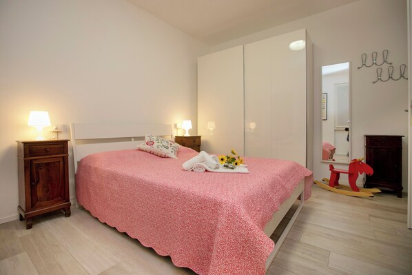 A bedroom with a bed, bedside tables, a wardrobe, and a rocking horse.