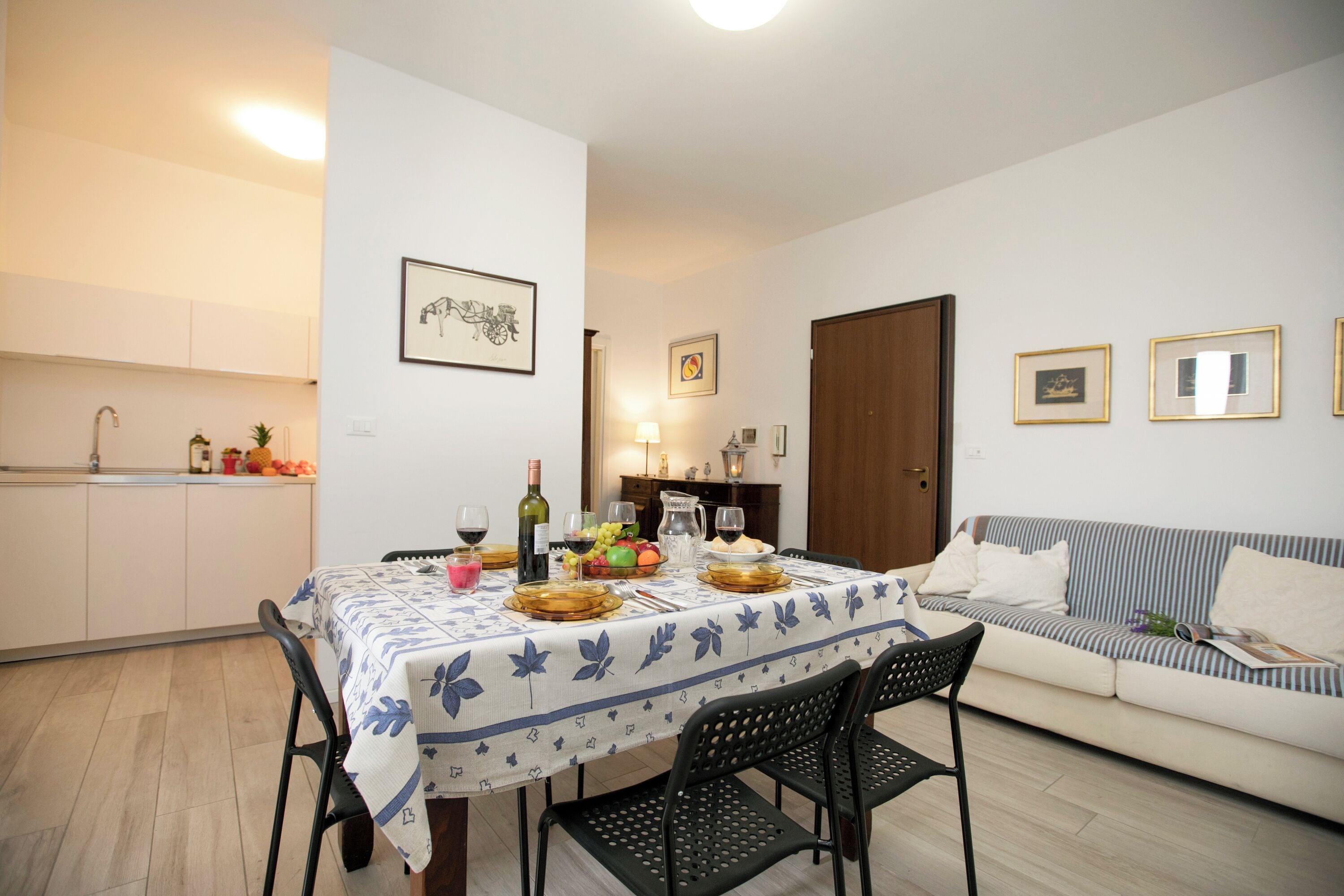 A dining area with a table set for four, a sofa, and a kitchen in the background.