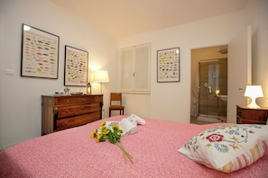 A bedroom with a bed, a dresser, a chair, a shower, and framed marine fauna posters on the wall.