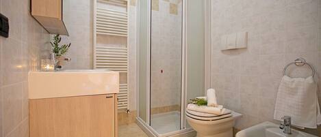Une salle de bain équipée d’une douche, de toilettes, d’un bidet et d’un lavabo.