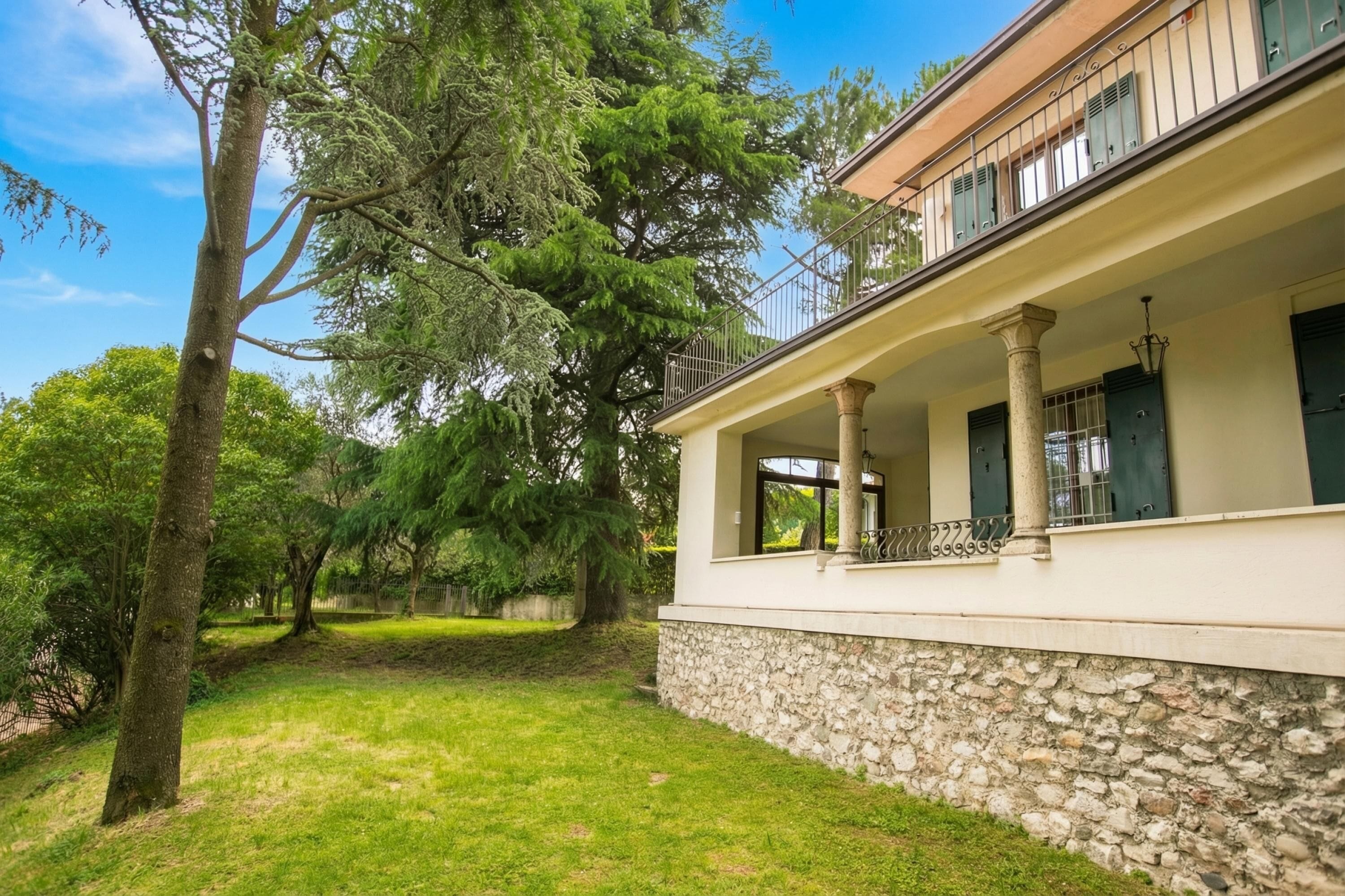 A building with a stone foundation, a balcony with metal railings, and a clear sky.