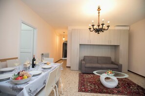 A dining area with a table set for four, a sofa, and a coffee table. - Villa Alberti Appartamento Bruna (Salò)