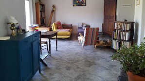 Una sala de estar acogedora con un sofá, una mesa de madera, una estantería y una planta en maceta.
