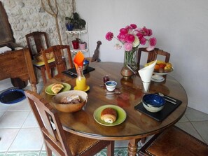 A dining table with various dishes, a vase of flowers, and a fruit bowl. - Mas Boheme (Espeluche)