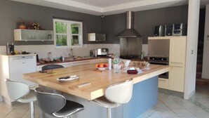 Una cocina moderna con una isla central, taburetes de bar, horno empotrado y microondas.