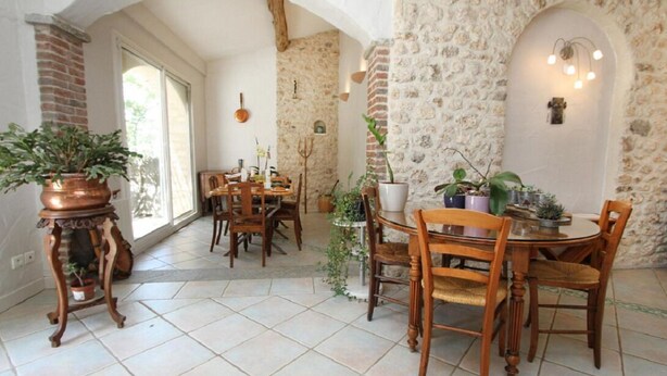 Un comedor con paredes de piedra, muebles de madera y plantas en macetas.