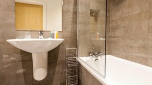 Un bany amb un lavabo amb peu, una cabina de dutxa de vidre i una banyera gran.