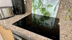 Eine Küche mit einer schwarzen Induktionskochplatte, einem Toaster und einer Kaffeemaschine.