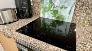 A kitchen with a black induction cooktop, a toaster, and a coffee maker. - GREEN MAR F 205 (Pals)