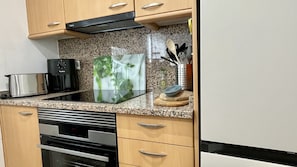 A kitchen with a microwave, toaster, and a glass-top island with a plant. - GREEN MAR F 205 (Pals)