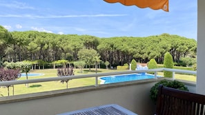 A balcony with a view of a swimming pool, surrounded by trees and a grassy area. - GREEN MAR F 205 (Pals)
