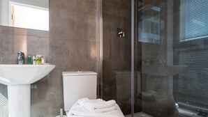 Ein modernes Badezimmer mit Waschbecken, Toilette und Duschkabine aus Glas.