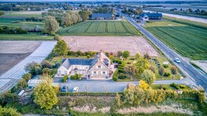 Vue aérienne d’un vaste domaine comprenant une maison principale, de vastes champs et une route.