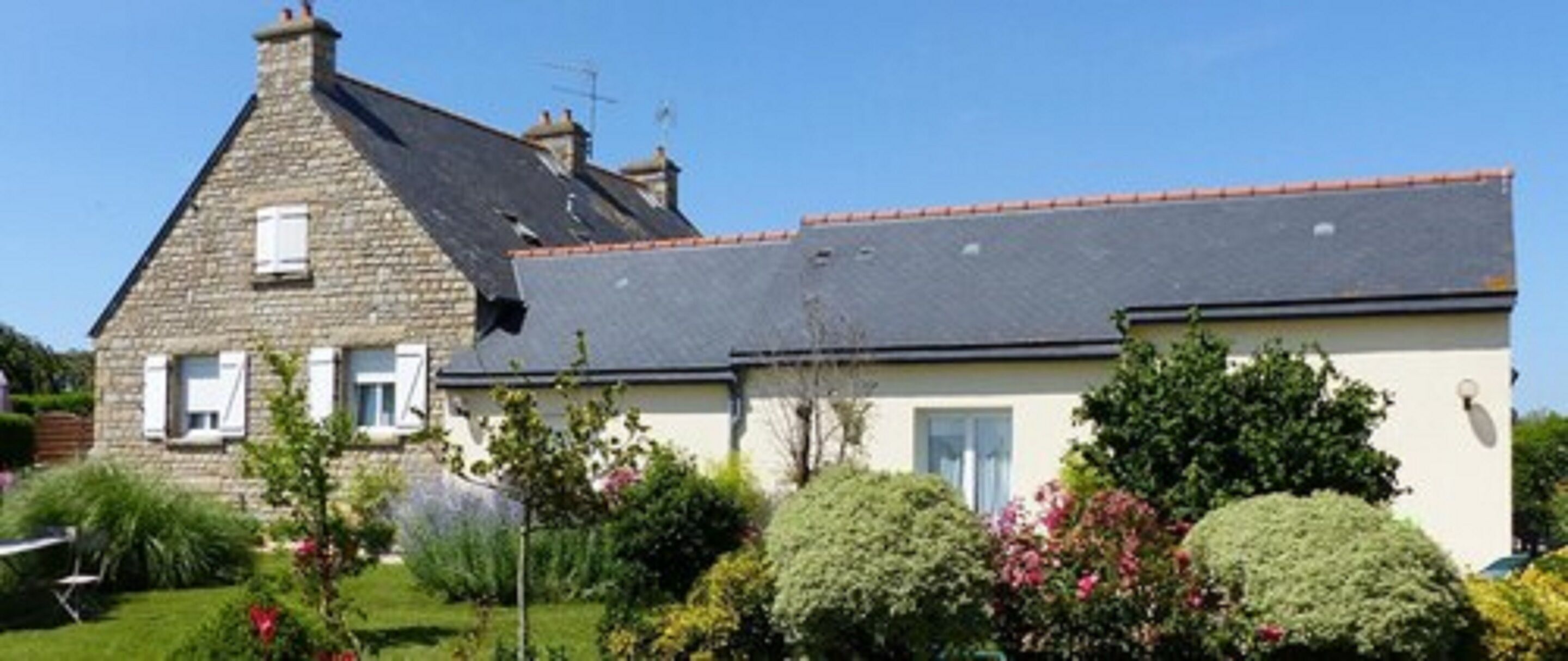 A two-story house with a stone facade and a tiled roof.