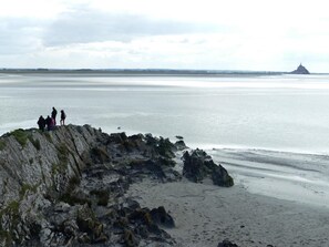 Eine felsige Küstenlinie mit einer kleinen Gruppe von Menschen, die auf einem Felsen über das Meer schauen.