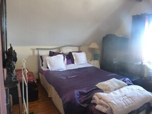 A bedroom with a bed, pillows, a nightstand, a lamp, and a window with curtains. - Ms McCreadys Guest House (Doncaster)