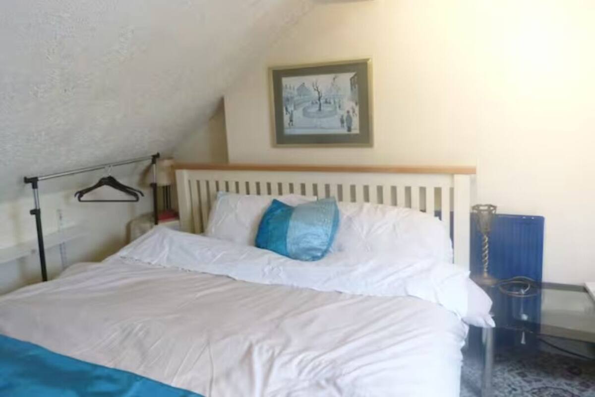 Um quarto com uma cama, um quadro na parede e um radiador.
