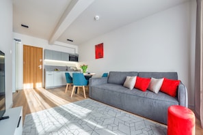 A modern living room with a grey sofa, red cushions, and a geometric rug. - Sun & Snow Resorts A Białka Tatrzańska (Bukowina Tatrzanska)