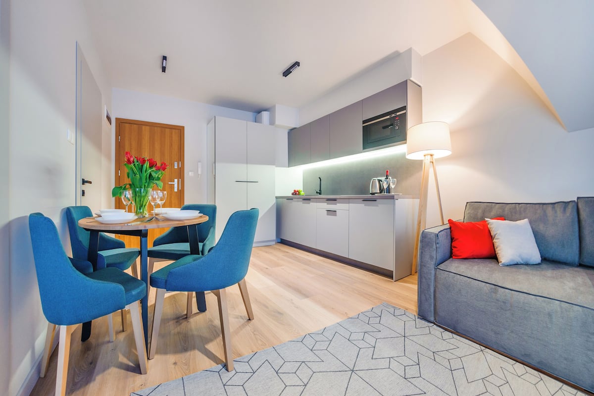 A modern living space with a dining area, kitchen, and a sofa.