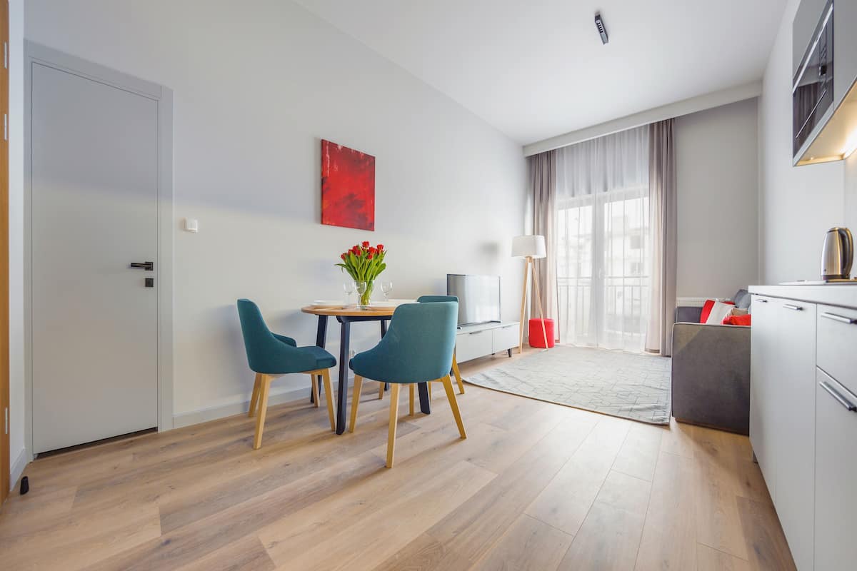 A modern hotel room with a dining area, a sofa, and a kitchen area.