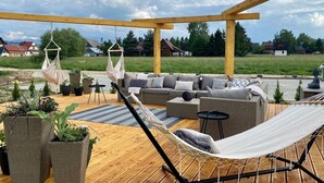 An outdoor patio with wicker furniture, a hammock, and potted plants. - Sun & Snow Resorts A Białka Tatrzańska (Bukowina Tatrzanska)