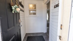 A hallway with a black door, a small window, and a doormat. - Downtown 1 Bedroom Charmer - Walk, Bike, Visit, Enjoy!! (Rapid City)