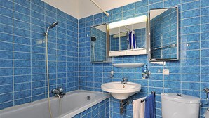 A bathroom with blue tiled walls, a white bathtub, a sink, and a toilet. - Hotel Blanco (Hamburg)