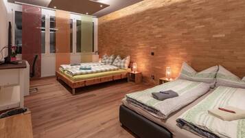 Un dormitorio con dos camas, suelo de madera y pared de ladrillo.
