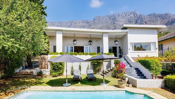 Ein modernes Haus mit Swimmingpool, zwei Liegestühlen und einer Treppe, die zum Eingang führt.