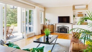 Ein geräumiges Wohnzimmer mit großem Fernseher, bequemen Sitzgelegenheiten und einem Kamin.