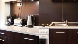 Una cocina moderna con armarios de madera oscura, encimera blanca, horno integrado, placa de cocina y fregadero.