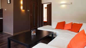 Una sala de estar moderna con un sofá blanco, una mesa de centro oscura y una pared de acento marrón.