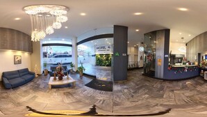A hotel lobby with a curved floor, a reception desk, a sofa, and a chandelier.