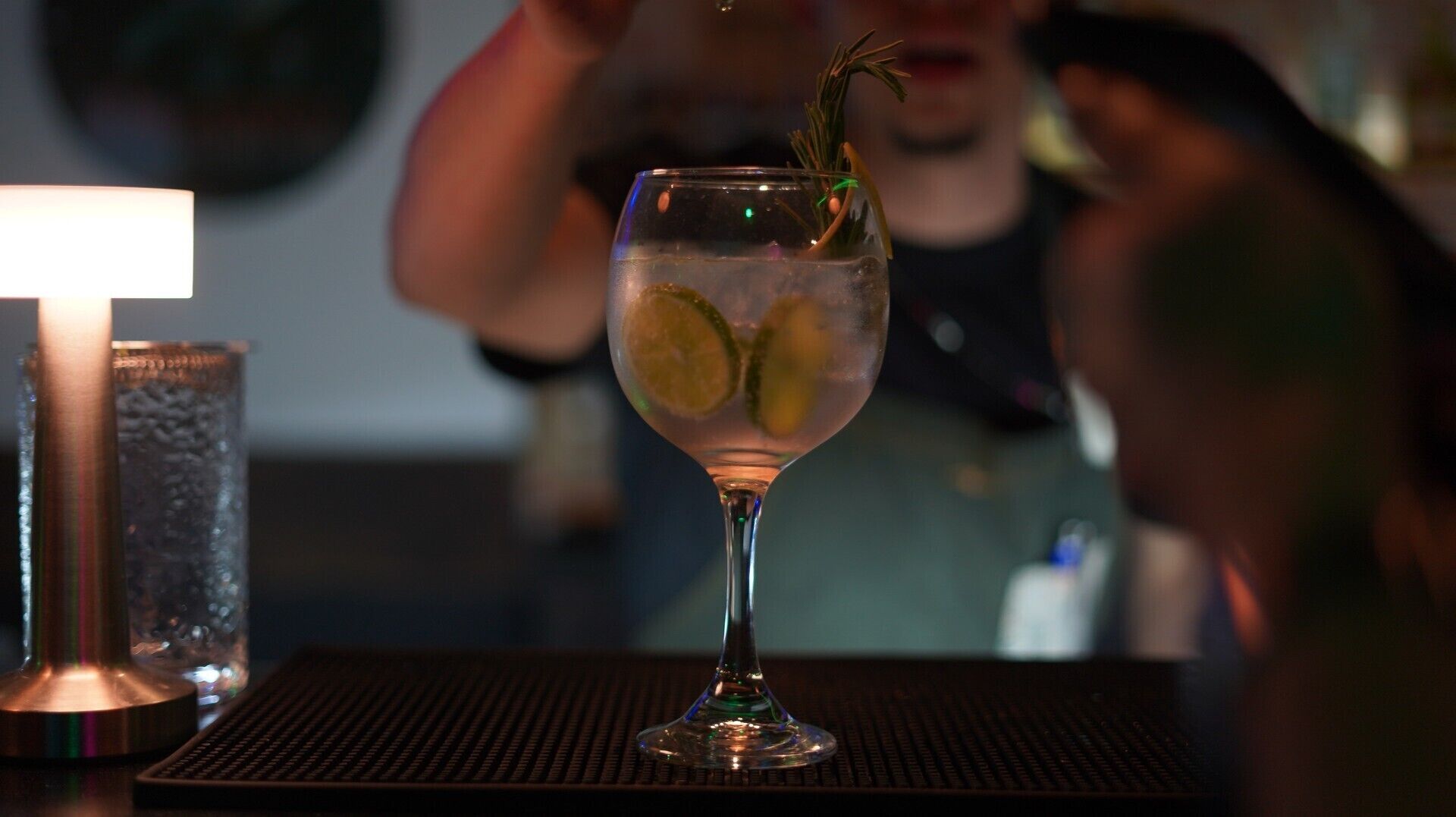 A cocktail glass with a lime slice garnish on a bar counter.