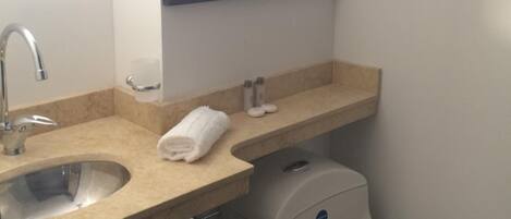 Un baño con lavabo, espejo, inodoro y toallero.