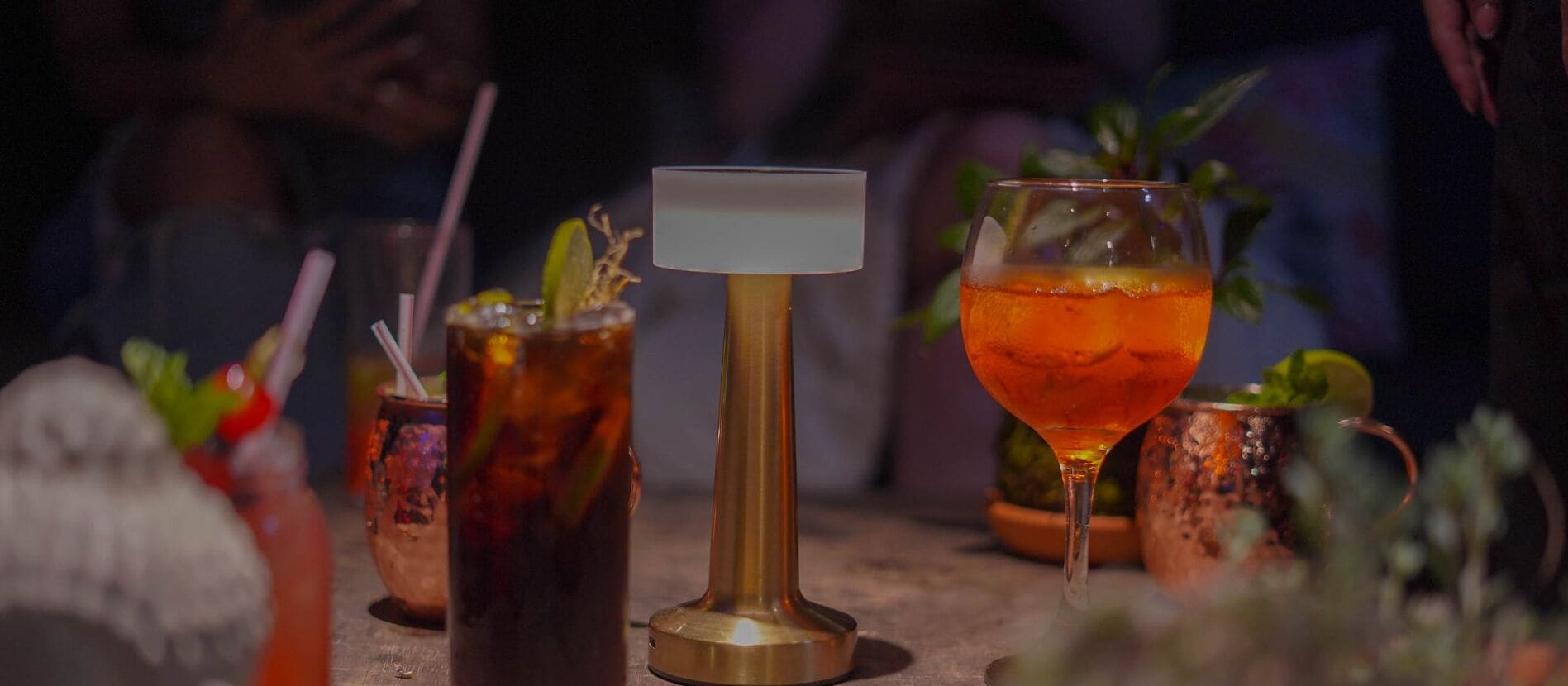 A bar setting with various drinks, a gold-colored bar stand, and a copper mug.