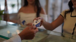 A person holding a hotel key card at a reception desk. - Hotel H53 (Sogamoso)