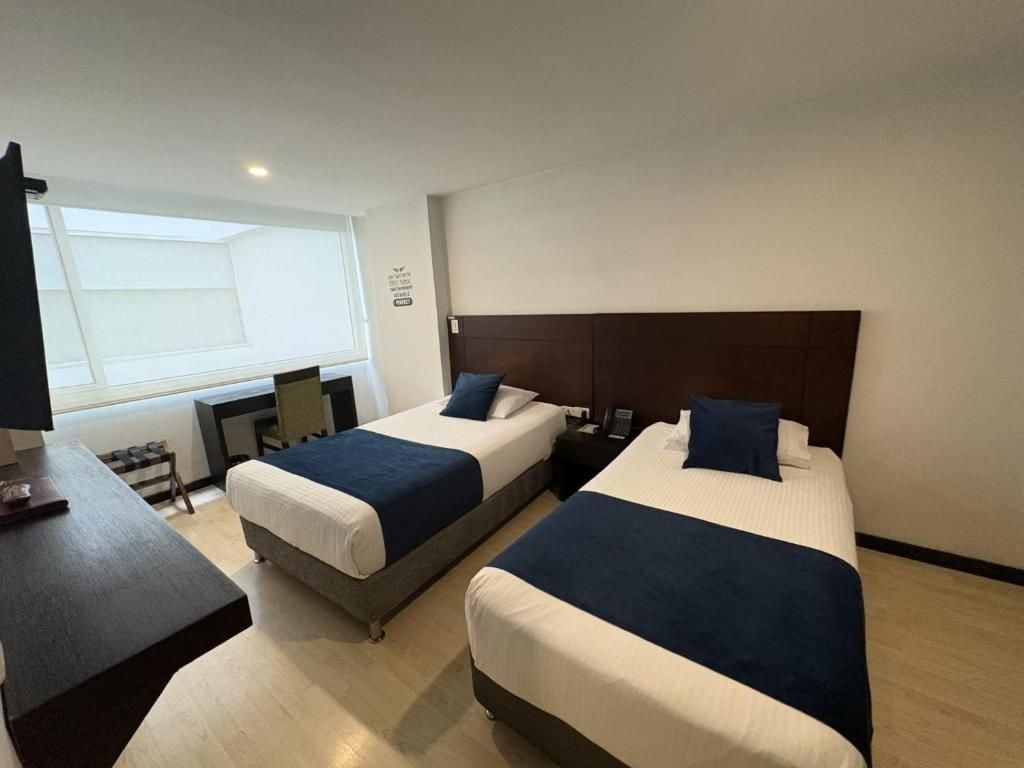 Una habitación de hotel con dos camas, un escritorio y una silla.