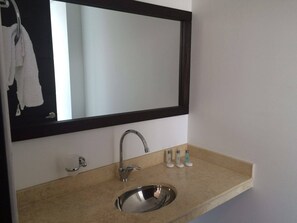 A bathroom with a sink, mirror, and toiletries. - Hotel H53 (Sogamoso)
