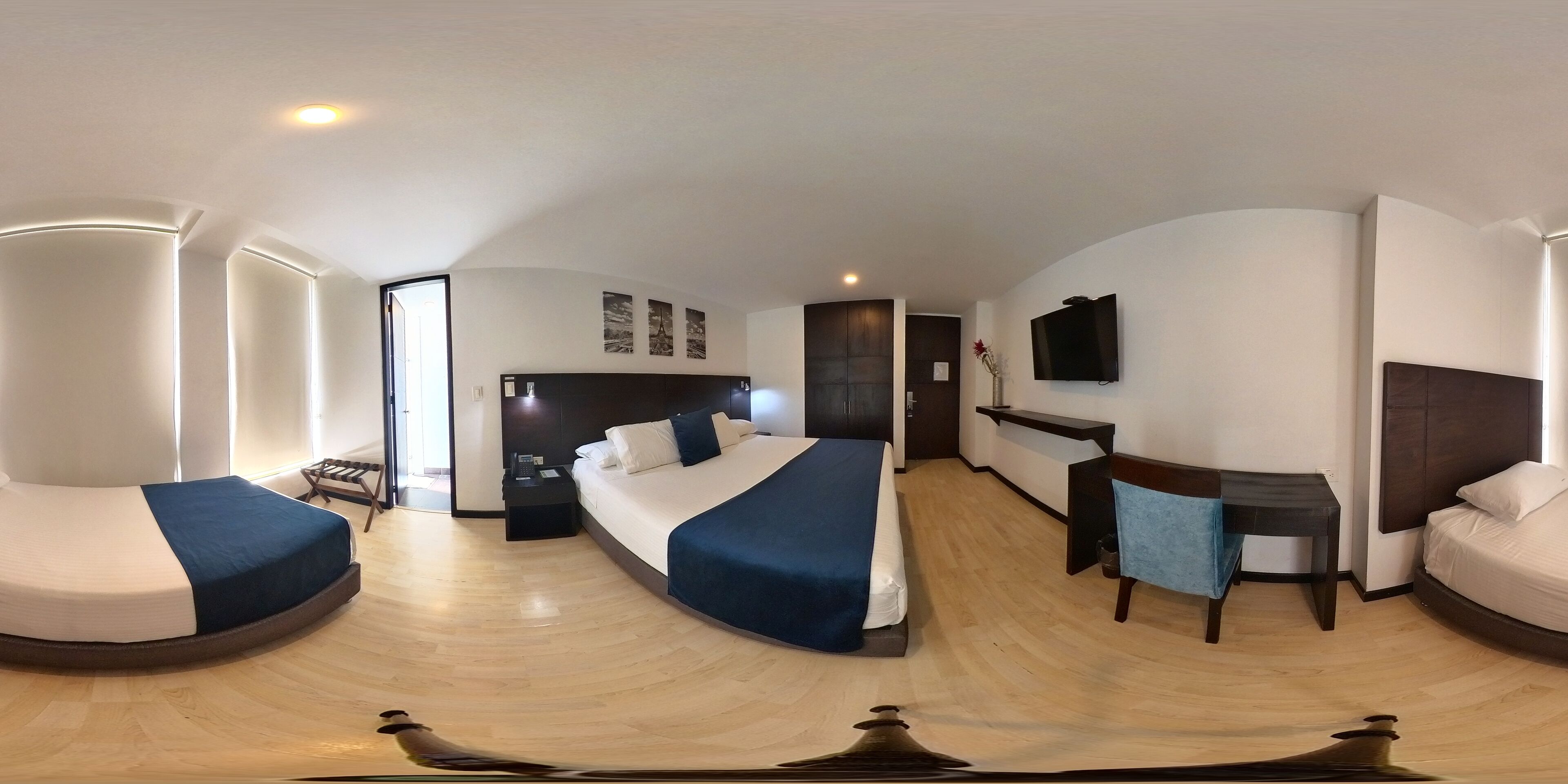 Een moderne hotelkamer met een gebogen bed, een bureau, een televisie en een zithoek.