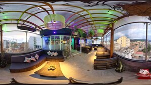 A modern interior with a curved ceiling, seating areas, and large windows offering city views.