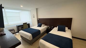 Una habitación de hotel con dos camas, un escritorio y una silla.