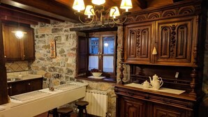 Una cocina rústica con paredes de piedra, armarios de madera y una encimera larga con taburetes.