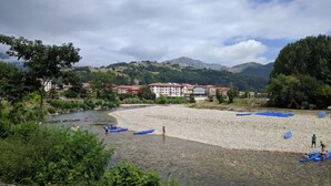 Una zona junto al río con una playa de arena, barcos y edificios al fondo.
