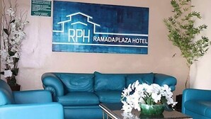 A blue sofa and a coffee table with a floral arrangement in a hotel lobby. - Tis Hotel 153 (Prata)