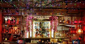 A bar with a variety of liquor bottles, a sign reading 'MART ROAD,' and a decorative archway. - Cherry Bar Rooms (London)