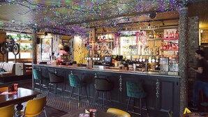 A bar area with a counter, stools, and a variety of bottles and glasses. - Cherry Bar Rooms (London)